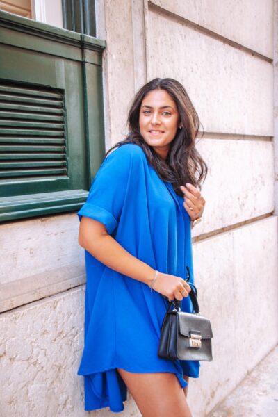 Alfama é um vestido azul escuro estilo camiseiro oversized, o que o torna um modelo confortável. É um vestido curto, fluido e versátil, perfeito para várias ocasiões.