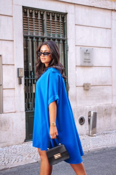 Alfama é um vestido azul escuro estilo camiseiro oversized, o que o torna um modelo confortável. É um vestido curto, fluido e versátil, perfeito para várias ocasiões.